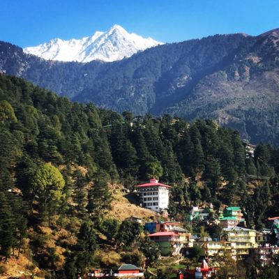 Snow-capped mountains loom over colourful houses and lush greenery in Dalhousie.