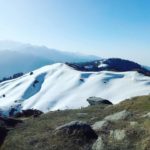 Mountain landscape with snow-covered peaks and clear blue sky.