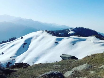 Mountain landscape with snow-covered peaks and clear blue sky.