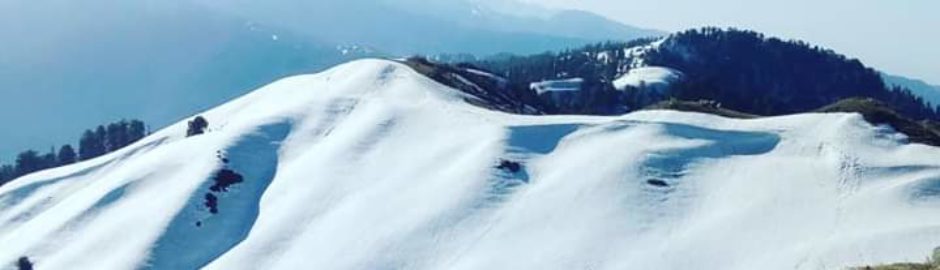Mountain landscape with snow-covered peaks and clear blue sky.