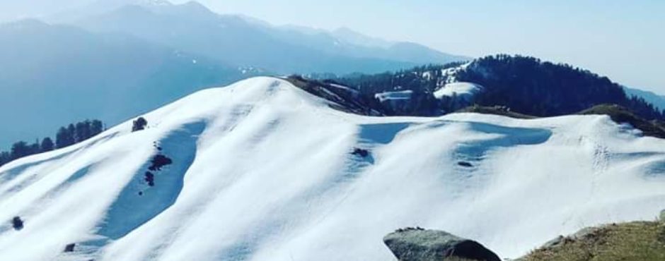 Mountain landscape with snow-covered peaks and clear blue sky.